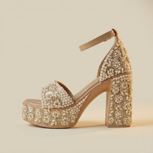 Beige high-heeled shoe with pearl embellishments on a beige background